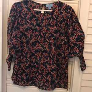 Adorable light weight top with little ties at the end of the sleeves.